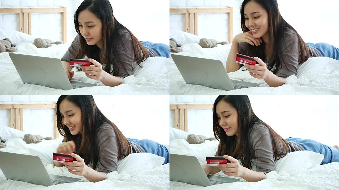 年轻女子在床上使用笔记本电脑在网上购物