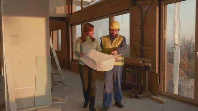 建筑师抱着他的计划，让女人参观了她正在建造的房子。