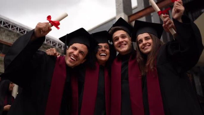 多元化的朋友拥抱并庆祝他们的大学文凭微笑