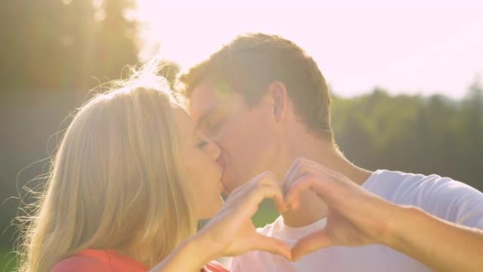 慢动作: 微笑的男人和女人亲吻，同时用手指做心形。