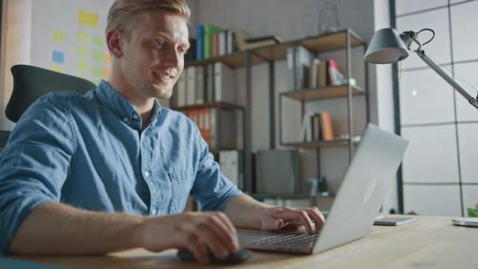 英俊的金发商人坐在办公室的办公桌前，用笔记本电脑工作。创意企业家使用计算机从事软件独角兽创业项目。低