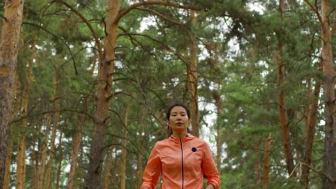 亚洲妇女在松树林中奔跑