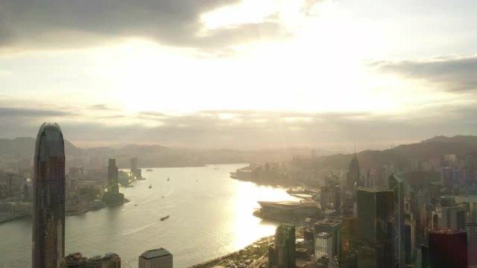 香港城市天际线和sunflares 4k股票视频的鸟瞰图日出。无人机正在向后飞行。