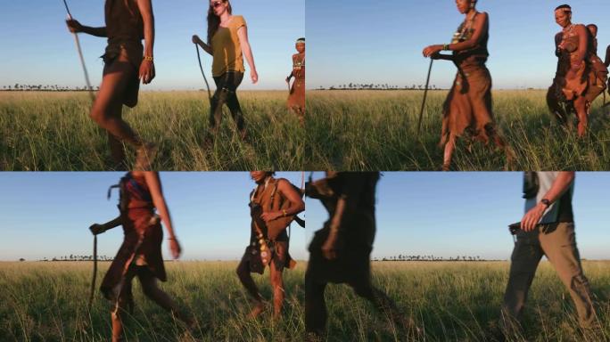 在博茨瓦纳的Makgadikgadi草原上，一群游客与San人/Bushman穿着传统服装在灌木丛中