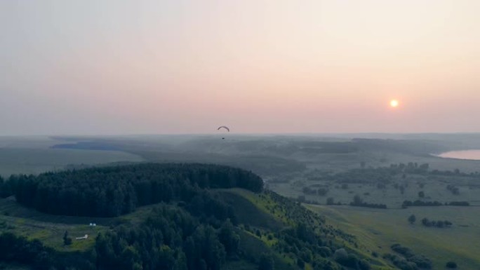 人在天空的日落背景上漂浮着滑翔机。滑翔伞，动作，极限运动概念。