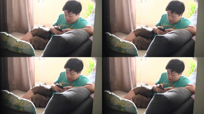 一名亚洲华裔中年妇女下午在客厅的沙发上上网浏览智能手机
