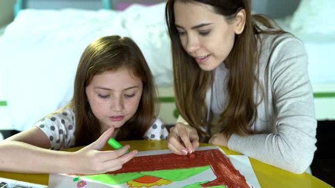 母亲正在帮助女儿在房子的桌子上画一幅无法去任何地方的画。传达母亲对孩子的爱和承诺