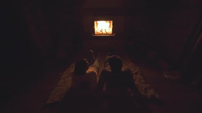 坐在壁炉旁的地板上的年轻夫妇