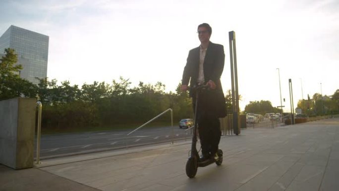 低角度: 穿着正装的男人在阳光普照的城市骑着踏板车去面试。