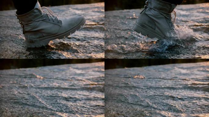 日落慢动作时，穿着灰色防水沙漠鞋的男性腿的特写镜头直接走进水流。