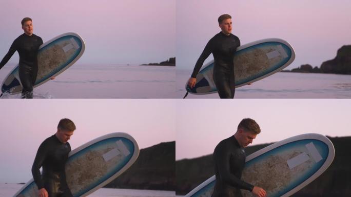 走出大海时穿着潜水衣背着冲浪板的男子