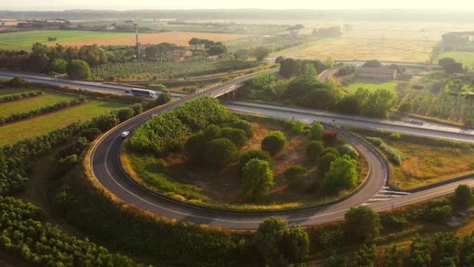 空中无人机镜头: 长途半卡车在意大利农村地区繁忙的高速公路上行驶。美丽的自然风光与人类物流进步