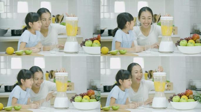 孕妇和她的女儿在搅拌机中混合水果冰沙。