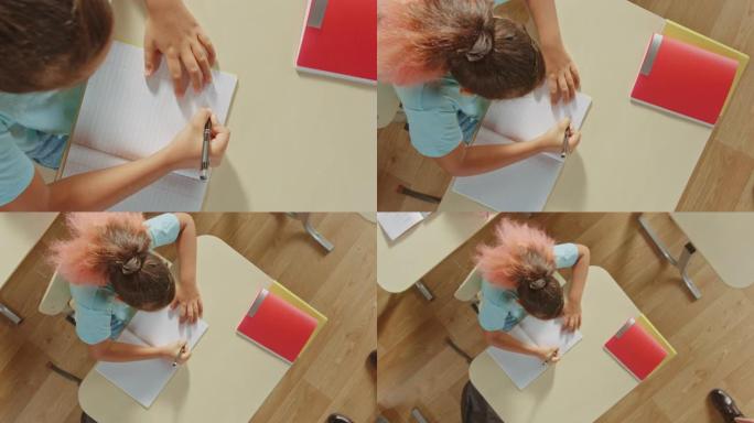 缩小俯视摄像头: 小女孩在学校里，在她的运动笔记本上写字。垂直屏幕方向9:24的视频素材