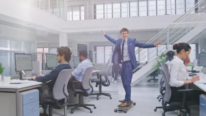 穿着西装和领带的年轻快乐英俊的经理骑着长板。在现代开放式办公室中，多元化且积极进取的商人在计算机上工