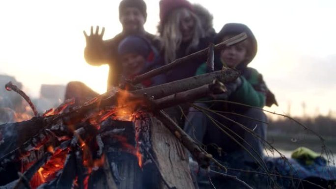 家庭在篝火晚会上热身。冬季乐趣。城市中的河边