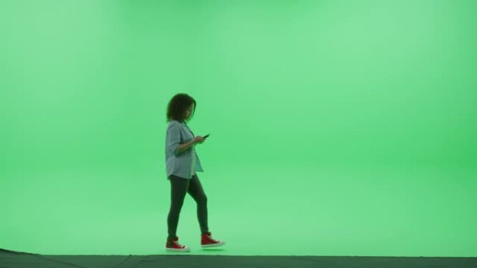 绿屏色度钥匙工作室: 穿着时尚休闲服的年轻女孩使用智能手机，通过互联网浏览，社交媒体上的聊天从左到右