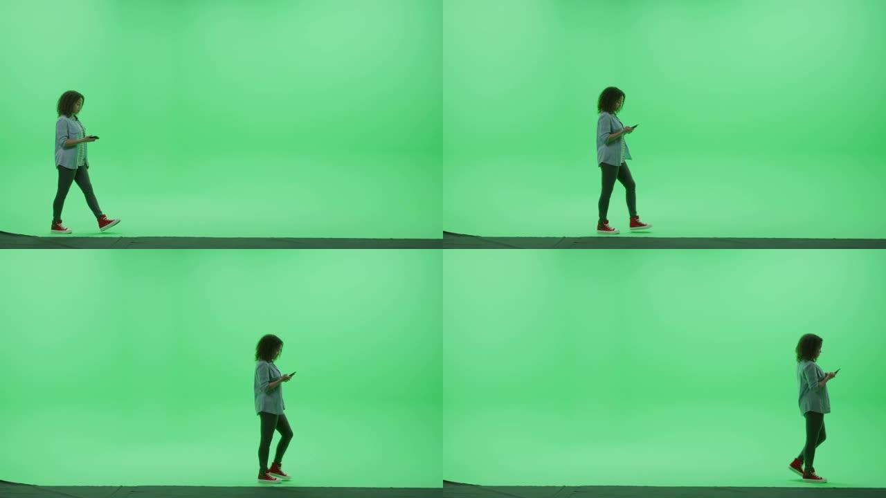 绿屏色度钥匙工作室: 穿着时尚休闲服的年轻女孩使用智能手机，通过互联网浏览，社交媒体上的聊天从左到右