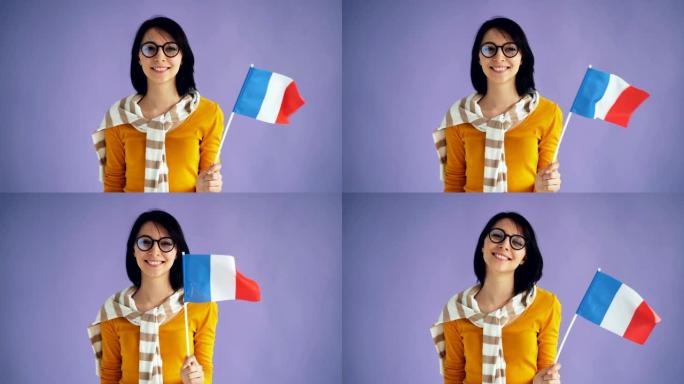 戴着眼镜的可爱的年轻黑发女人的慢动作拿着法国国旗微笑