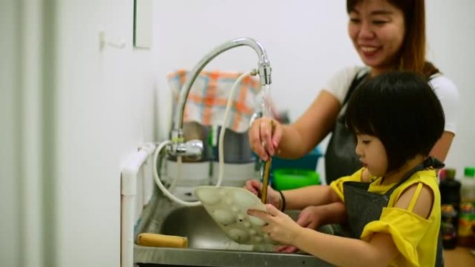 一位亚洲华裔女美术老师在水彩画课后帮助她的学生清理所有画笔