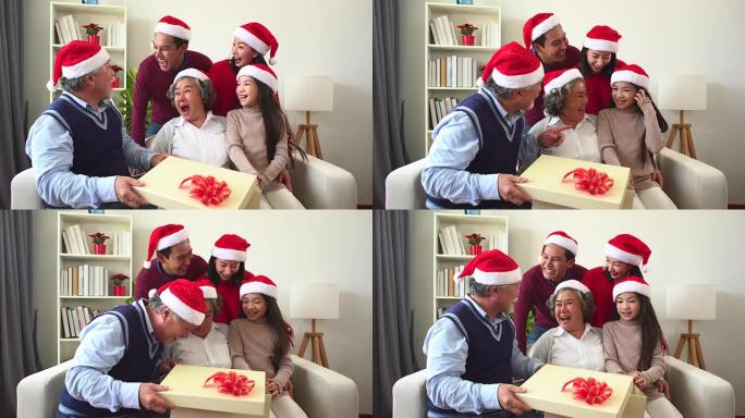 一群幸福的家庭打开圣诞礼物。祖父大胡子男人和他的家人有可爱的女儿圣诞树背景。花时间和你的家人在一起。