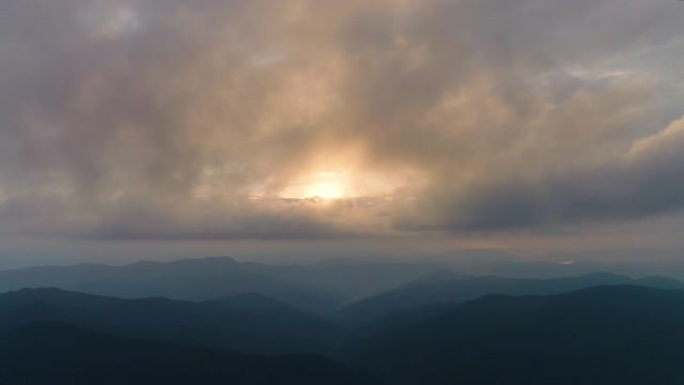 日落背景下在山上云层中的飞行。过度下垂