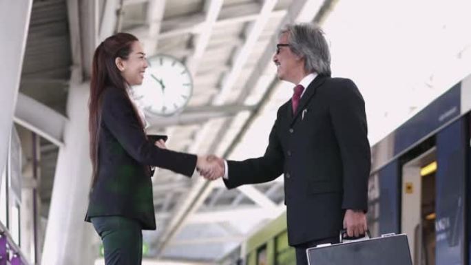 亚洲女商人在地铁站与男人握手的慢动作。