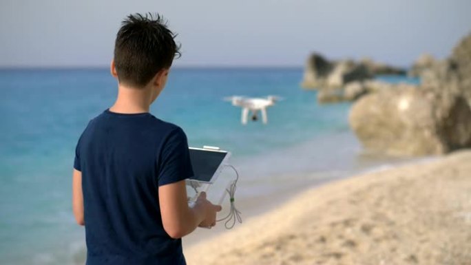 小男孩在海边操纵无人机。UHD