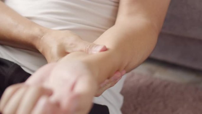4k分辨率亚洲男子在家按摩手臂疼痛受伤。医疗保健和医疗概念。
