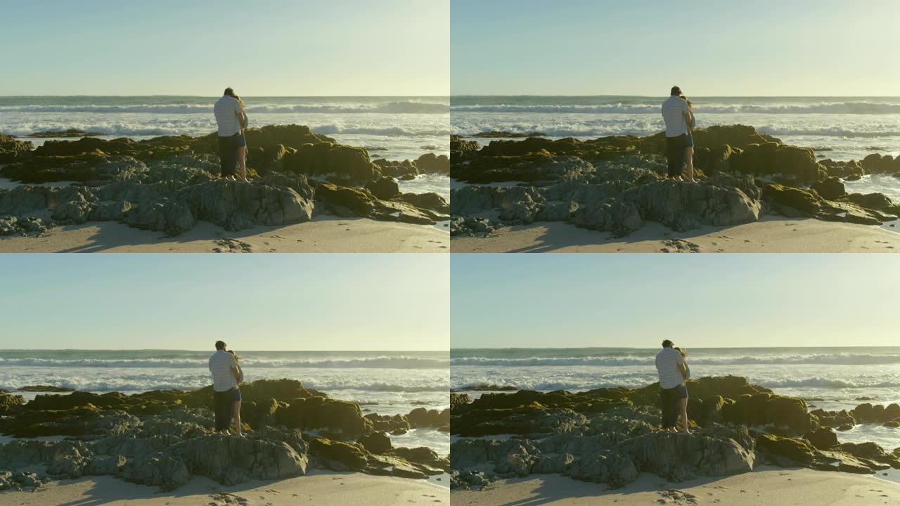 一对情侣站在4k海滩的岩石海岸上