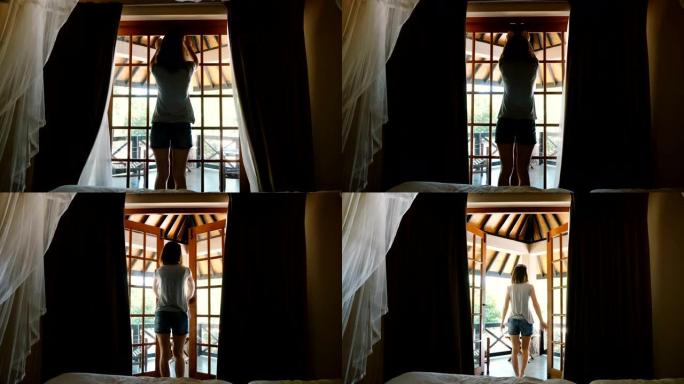 后视图美丽的年轻幸福的女人打开酒店小屋窗帘和窗户门，走到令人惊叹的阳光明媚的露台。