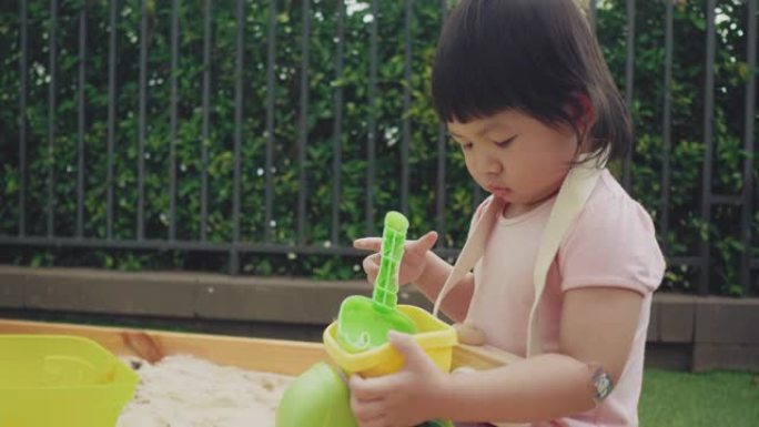 亚洲女婴在后院的沙箱外面玩耍