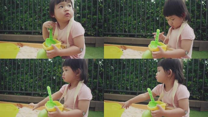 亚洲女婴在后院的沙箱外面玩耍