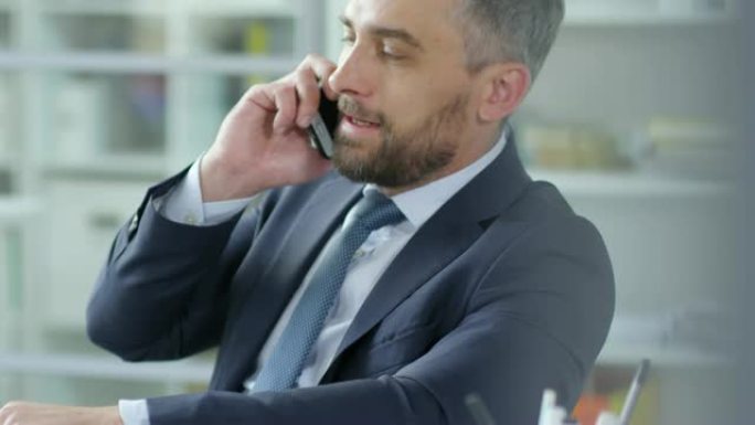 成功的商人在办公桌前用钱在电话里聊天