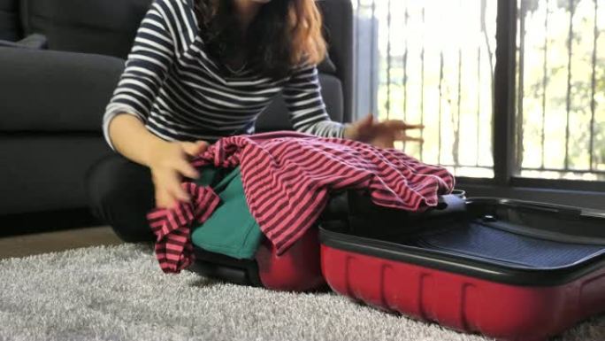 女人坐在装满的手提箱上