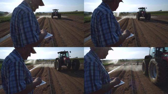 使用数字平板电脑的农民的4k裁剪视图，监视拖拉机在大型蔬菜农场上用农药喷洒新耕作的土壤