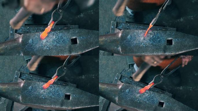 工作铁匠用铁锤敲打铁砧上的金属刀。