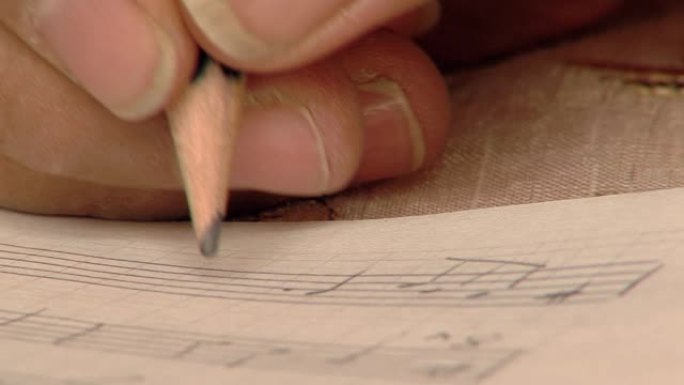 男性在乐谱上用铅笔手写笔记。