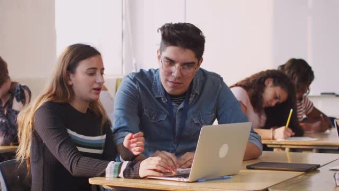 男老师为在笔记本电脑上工作的女学生提供一对一的支持