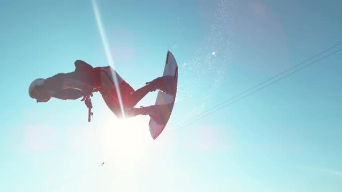 镜头耀斑: 快乐的wakesurfer在飞越相机时做了一个很酷的翻转技巧