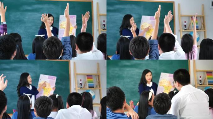 男生站在课堂上举手回答讲座时的后视。学校的学生举手问讲师一个问题。