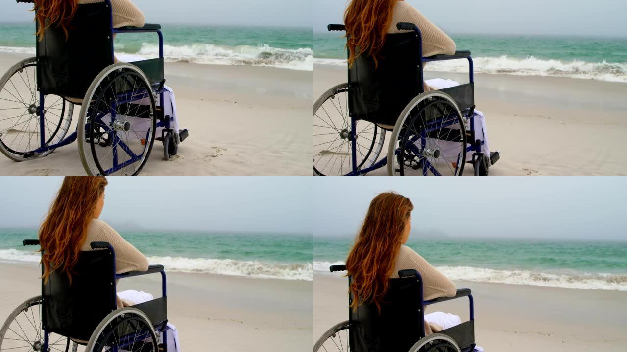 在海滩4k坐在轮椅上的女人的后视图