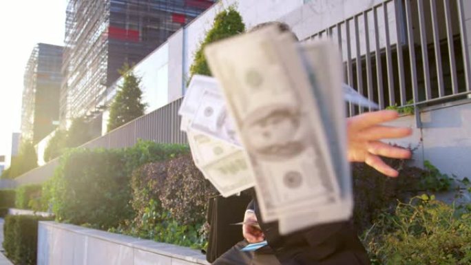 慢动作肖像: 快乐的商人向相机扔了一堆钱。
