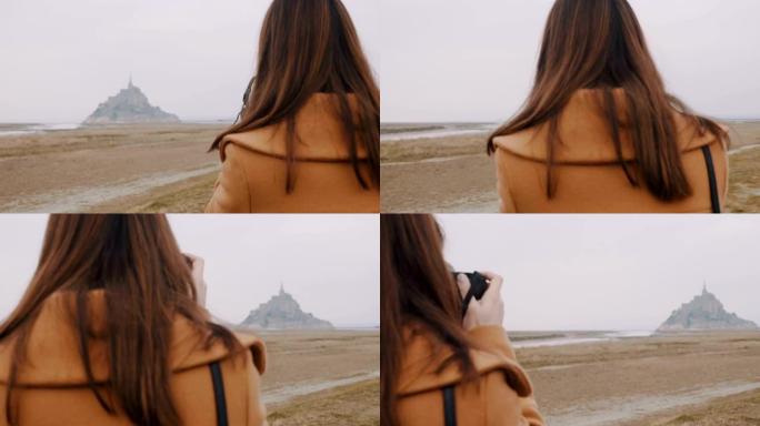 美丽的黑发摄影师女人在阴天慢动作拍摄史诗般的雾蒙蒙圣米歇尔岛。