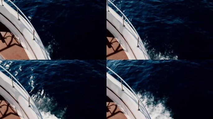 白色游艇正面的美丽俯视图在晴朗的晴天在公海航行，切割深蓝色的海浪。