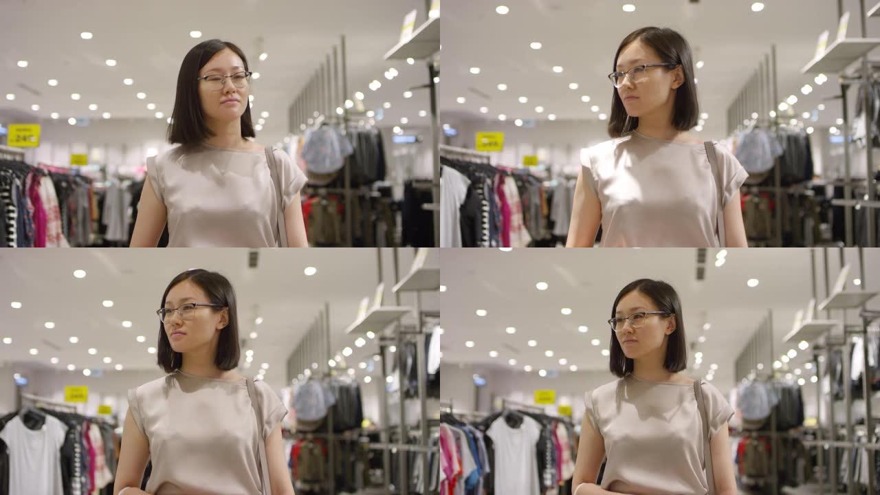 年轻的亚洲妇女走过服装店，环顾四周