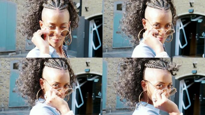 穿着蓝色连衣裙的时尚年轻黑人女性转身看着太阳镜，特写镜头