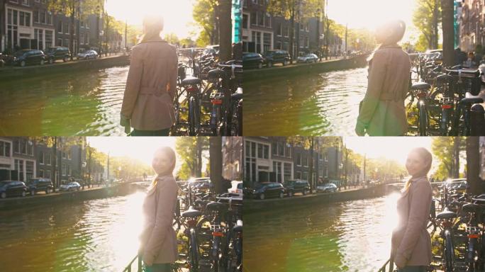 阿姆斯特丹阳光明媚的日子，女人站在运河旁，对着镜头微笑