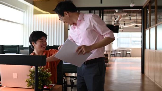 2位亚洲华裔同事在办公室用新的握手方式互相问候，戴着防护面罩