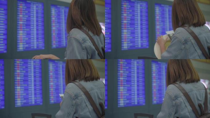 慢动作-快乐的亚洲妇女在国际机场登机口的候机楼大厅里看着信息板，用行李检查她的航班。生活方式女性在机